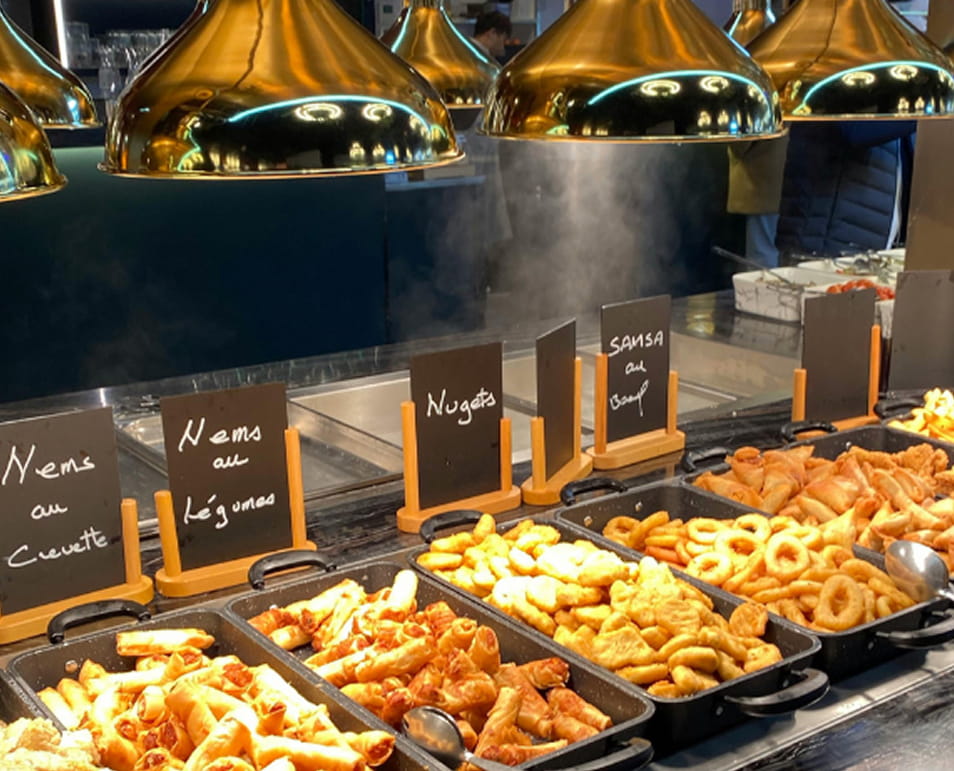 Hot buffet station with fried appetizers under brass heat lamps and handwritten menu signs
